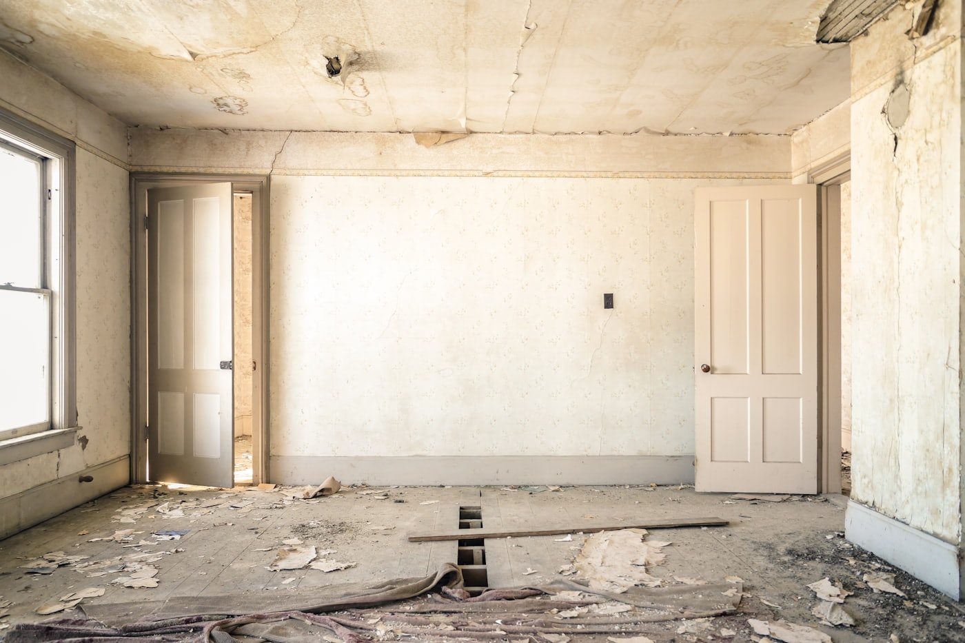 Tired room with peeling wallpaper and damaged floor