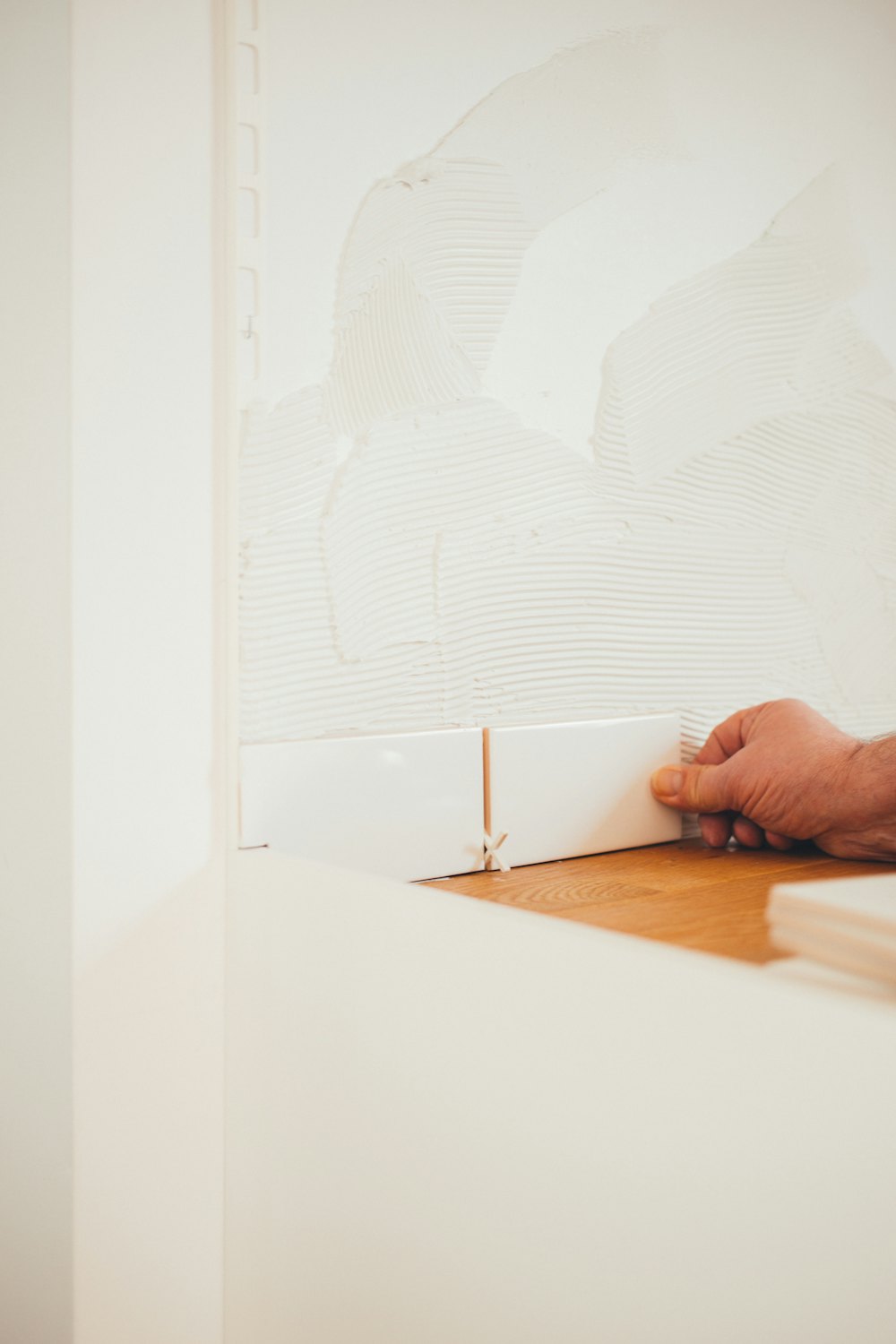 Hand setting a white tile into fresh adhesive