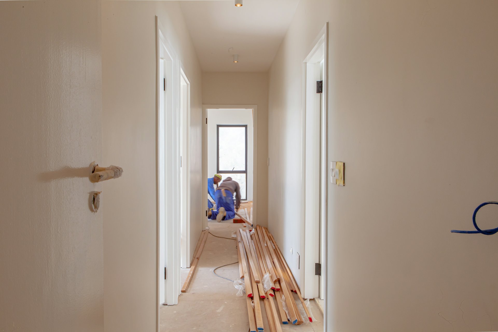 Trades working inside a house mid renovation with timber stacked in the hallway