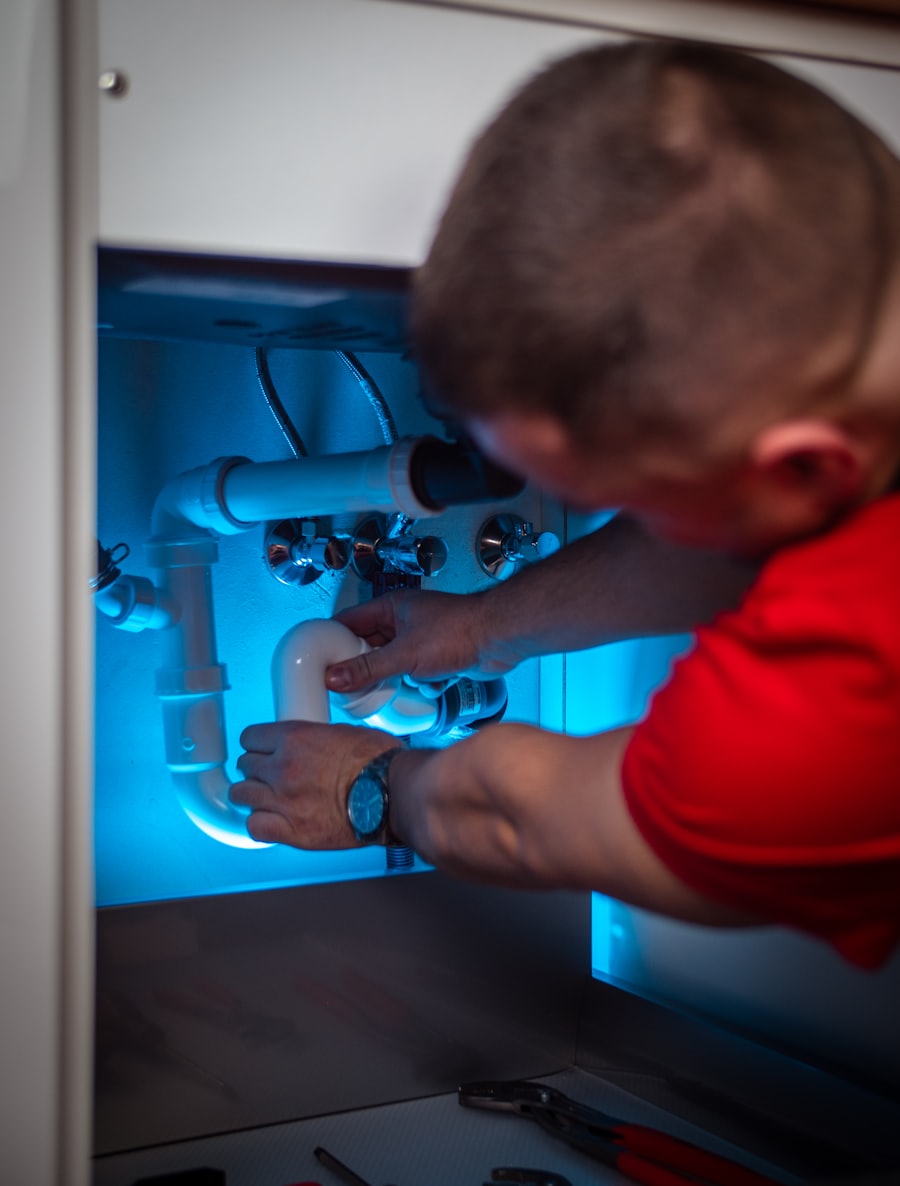 Plumber working on pipework under a sink